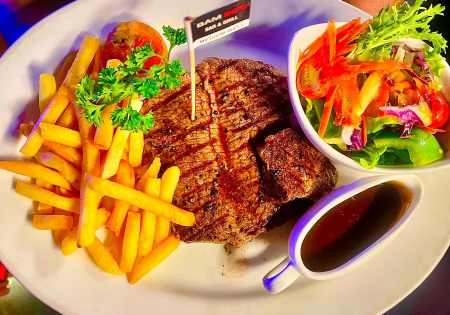 A grilled steak at Bamboo with chips, garden salad and gravy, served with the Bamboo Bar and Grill pick in it